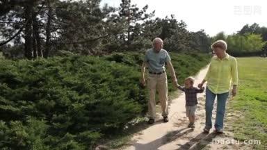 享受<strong>退休</strong>生活的爷爷奶奶和老人和他们的孙子在公园里度过时光，老人抱着